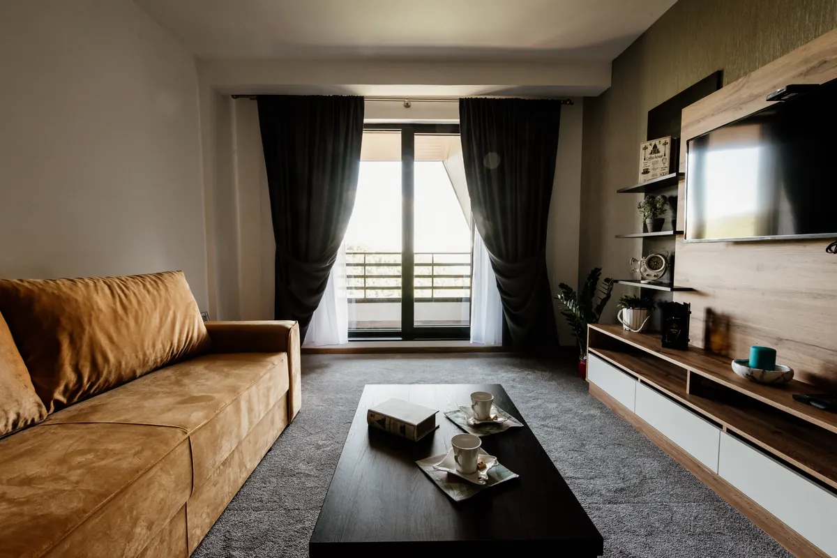 Salón moderno y luminoso de un piso con sofá, mesa de centro y salida a terraza